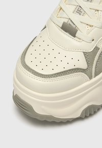 Lys kremfarget sneakers med rund design, laget av lær og semsket skinn, perforerte detaljer og en tykk gummisåle i en dempet grå nyanse.