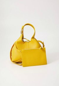 Gelbe Lederhandtasche mit strukturierter Oberfläche, runder Form, kurzem Griff und abnehmbarer flacher Tasche. Reißverschluss-Detail an der Tasche.