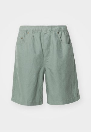 Light green shorts made of textured fabric with an elastic waistband, featuring two side pockets and minimal stitching details.