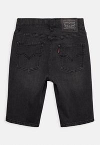 Pantalones cortos de mezclilla gris oscuro con un corte clásico, que presentan un parche de logo de cuero, dos bolsillos traseros y detalles de costura visibles.