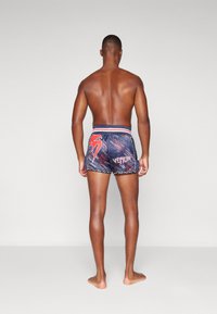 Schwimmshorts mit marineblauem Grund, roten und weißen Akzenten, Logo und dynamischem Muster. Weicher Stoff, elastischer Bund und kurzer Schnitt.