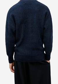 Suéter de punto azul marino con textura acanalada, mangas anchas y un corte relajado. Presenta un cuello redondo y llega hasta las caderas.