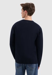 Marineblauwe sweatshirt met lange mouwen, een ronde hals en een zachte textuur. Het heeft raglanmouwen en een klassieke snit.