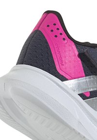 Zapatillas deportivas con parte superior de malla negra, acentos en rosa brillante, rayas plateadas y suela de goma blanca texturizada. Diseño duradero y ligero.