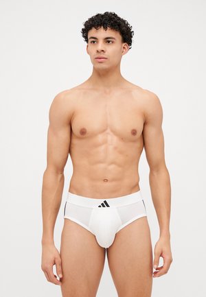 Weiße Baumwollslips mit einem schwarzen Bund, der drei Streifen aufweist. Der Stoff ist glatt und anliegend, entworfen für Komfort und Unterstützung.