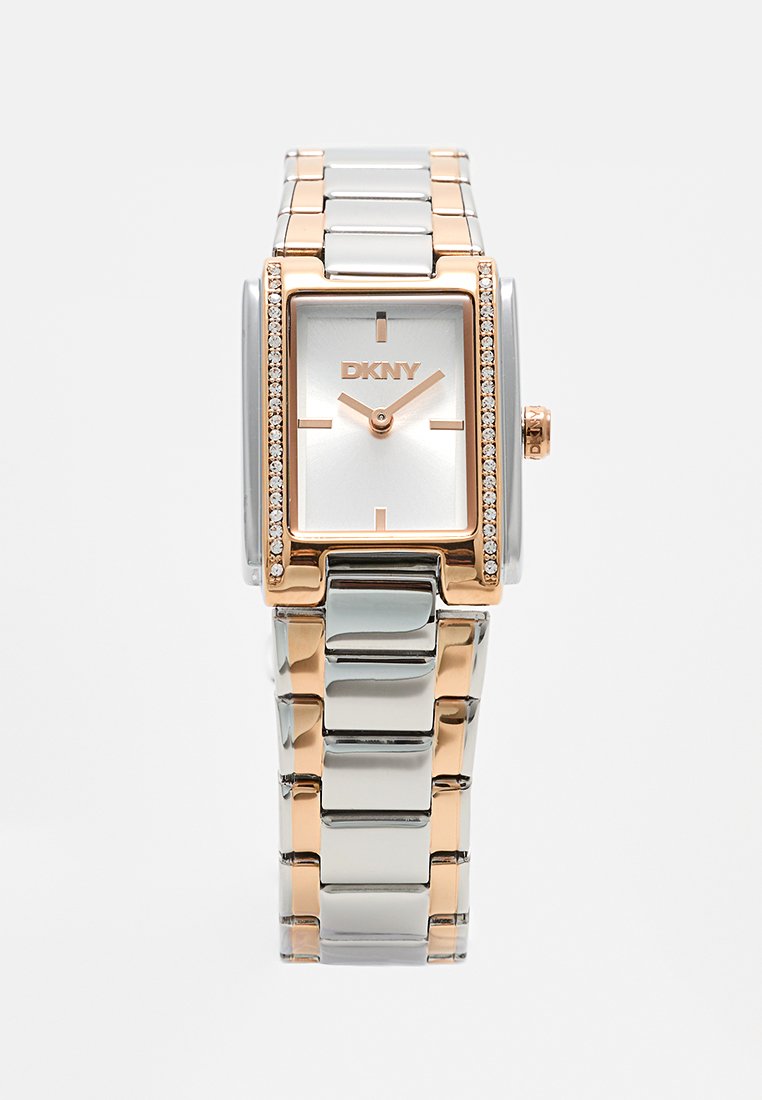 Srebrny i różowo-złoty zegarek na rękę DKNY z prostokątną tarczą, minimalnymi oznaczeniami na cyferblacie, kryształowymi akcentami po bokach i metalową bransoletą.
