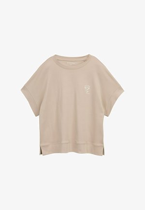 Világos bézs színű, rövid ujjú pulóver, kerek nyakú, oldalsó hasítékokkal az alján, és egy kis fehér virág hímzés az elején.