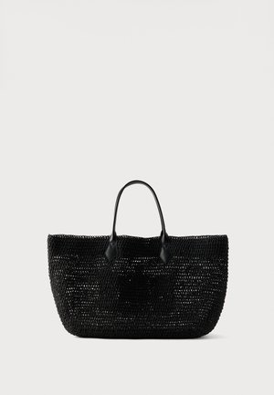Czarna pleciona torba typu tote z podwójnymi uchwytami i subtelnym wytłoczonym logo na froncie, przedstawiona na jednolitym jasnym tle.