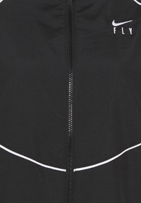 Chaqueta deportiva negra con cremallera completa, con acentos blancos a lo largo de las costuras y un pequeño logo. Tejido texturizado con un diseño ajustado.