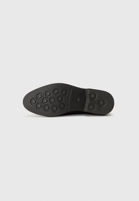 Black shoe sole made of rubber, featuring circular grip patterns, smooth edges, and a marked size (41) near the heel.