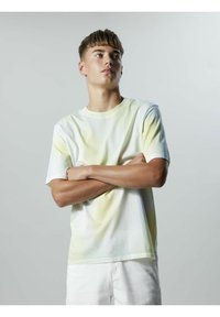 Camiseta de algodón blanca de manga corta con un diseño degradado en amarillo y verde, con cuello redondo y corte relajado. Textura suave.