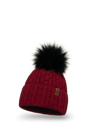 Beanie tricoté rouge avec une texture côtelée et à motif, présentant un pompon en fausse fourrure noire sur le dessus et une petite étiquette marron sur le côté.