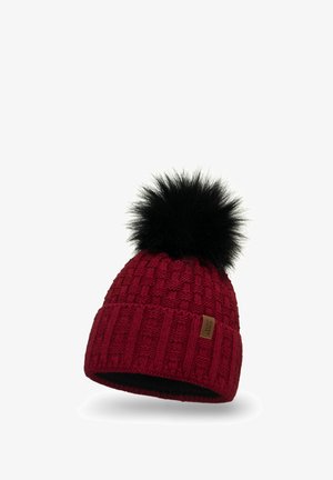Rode gebreide muts met ribbel- en patroontextuur, voorzien van een zwarte nepbont pompon bovenop en een klein bruin label aan de zijkant.