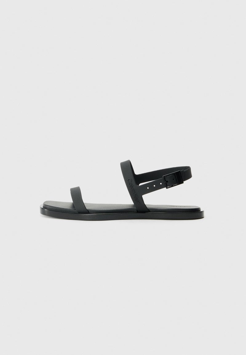 Black plastic sandals with two flat straps and a buckle closure. Features a textured footbed and a minimalist design.