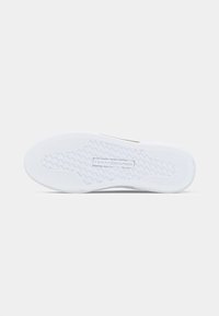 Talpa de sneaker albă cu un model texturat de aderență și logo-ul "Tommy Hilfiger" embossat în centru pe un fundal simplu.