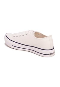 Zapatilla de lona blanca con puntera redonda, acentos azules a lo largo de la suela y diseño de cordones con seis ojales. Marca en el talón.