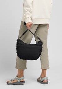 Borsa a spalla in tessuto nero con forma arrotondata, dotata di un bordo superiore morbido, doppi manici e una superficie testurizzata.