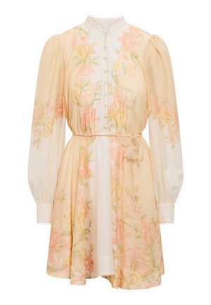 Robe courte à fleurs avec manches longues bouffantes, devant à boutons, ceinture à la taille, et motif floral pastel rose, jaune et vert sur tissu crème.