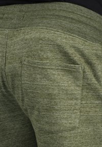 Žalios, tekstūruotos sportinės kelnės su briaunotu juosmeniu ir galine kišenė. Audinys turi švelnų, heather efekto išvaizdą, tinkamą kasdieniam dėvėjimui.