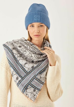 Blaues Strickmütze mit gerippter Textur, kombiniert mit einem dreieckigen grauen Schal, der Cartoon-Hunde und bunte geometrische Muster zeigt.