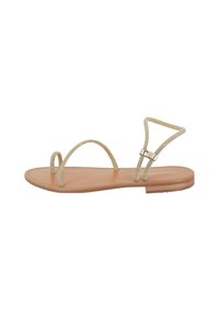 Sandali piatti dorati con sottili strisce incrociate e fibbia. Soletta in pelle marrone e suola piatta, caratterizzati da un design e dettagli minimalisti.