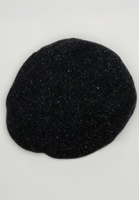 Cappello nero a motivo pied-de-poule realizzato in tessuto testurizzato, con forma rotonda e bordi leggermente rialzati. Materiale morbido e caldo.