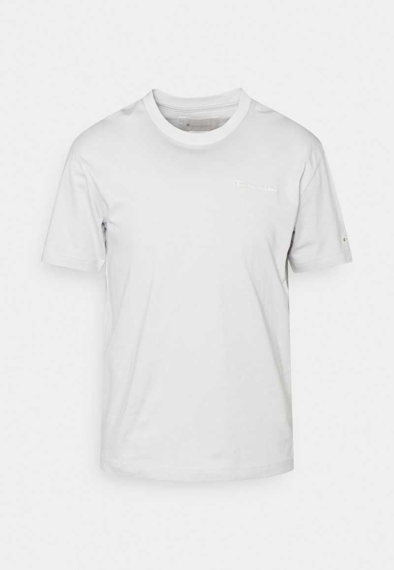 Vit bomull t-shirt med kort ärm, rundad halsringning och liten broderad logotyp på vänster bröst. Slät textur, minimalistisk design.