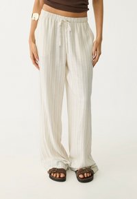 Pantalon large à rayures beige clair avec taille élastique et cordon de serrage. Fabriqué en tissu doux ; forme ample et fluide avec une coupe décontractée.