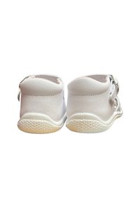 Zapatos de cuero blancos con forma redondeada, suelas texturizadas y un cierre lateral. Superficie lisa con acentos mínimos y forro suave.