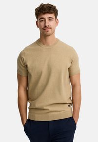 Suéter beige de manga corta con un cuello redondo, bordes acanalados y una forma ajustada. El material parece suave y ligero. Pequeña etiqueta con el logo en el dobladillo.