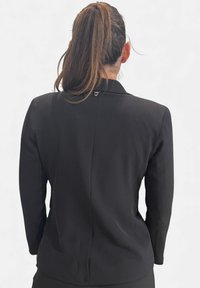 Blazer nero con maniche lunghe, design su misura, tessuto liscio, colletto con rever e un discreto accento metallico sulla parte posteriore.
