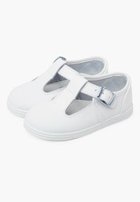 Scarpe T-strap bianche in pelle con ritagli, dotate di una fibbia argentata, suole in gomma e una finitura liscia. Progettate per comfort e facile vestibilità.