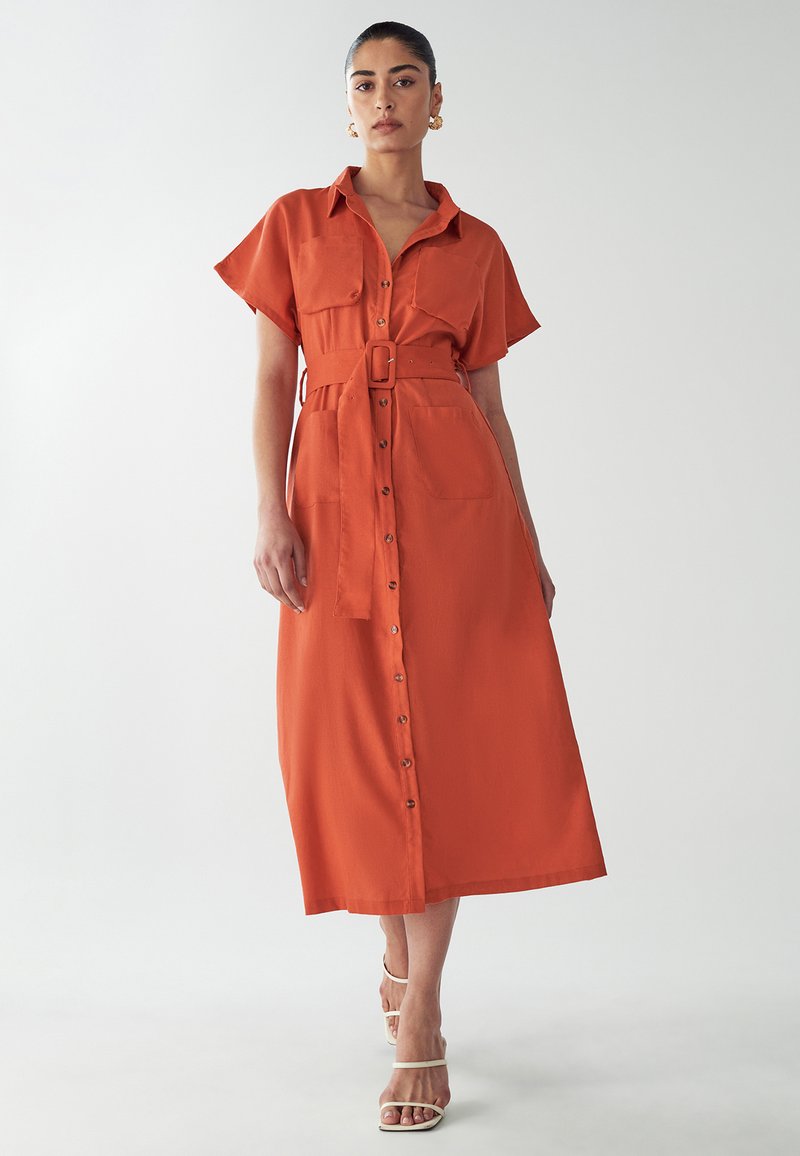 Button-up dress in deep orange, short sleeves, belted waist, knee-length, with two front pockets and a smooth, woven texture.
