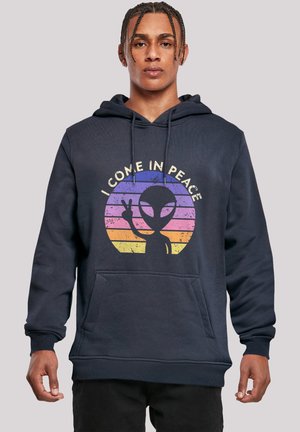 Marineblauer Hoodie mit Fronttasche, Kordelzug und Grafik eines Aliens mit dem Text "ICH KOMME IM FRIEDEN" in Gelb-, Rosa- und Orangetönen eines Sonnenuntergangs.