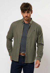 Camicia button-up verde oliva realizzata in tessuto intrecciato, con colletto classico, bottoni a contrasto e un piccolo logo ricamato sul petto.