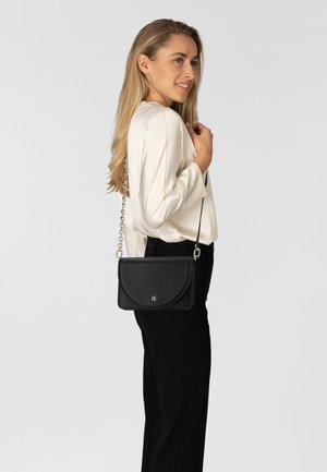 Schwarze Lederhandtasche mit weichem, strukturiertem Finish, geschwungenem Überschlag, silberner Kettenriemen und dezentem Logodetail.