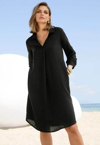 Schwarzes Leinenkleid mit Kragen, langen Ärmeln und lockerer Passform, mit einem leicht abgerundeten Saum und minimalistischem Design.