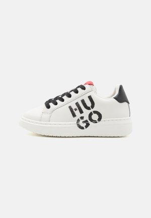 Baskets en cuir blanc avec des lacets noirs, présentant un logo "HUGO" en noir bien en vue. Accent rouge à l'arrière. Semelle plate pour un usage décontracté.