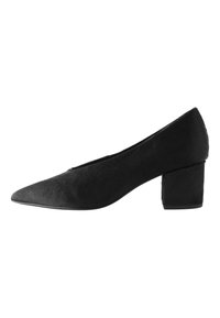 Svart lågklackad damsko med spetsig tå och texturerat mockaliknande material, sedd i profil mot vit bakgrund.