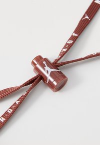 Red braided shoelace with a plastic aglet displaying a white Jordan logo. The aglet has a cylindrical shape and a glossy finish.