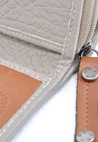 Grijs textuur leer wallet interieur met tan accenten, voorzien van witte stiksels en een zilveren rits. Opvallende hardware omvat een gestempelde knop.