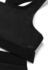 Brasile sportivo nero realizzato in tessuto liscio, con una fascia nera testurizzata e un accento lucido con logo. Design a schiena incrociata con spalline regolabili.