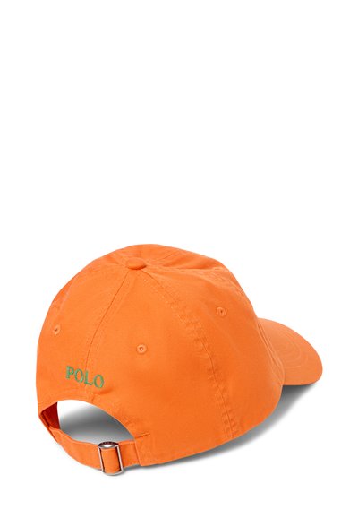 Oranje katoenen pet met een gebogen rand, verstelbare metalen strap en geborduurd "POLO" logo in het groen op de achterkant.