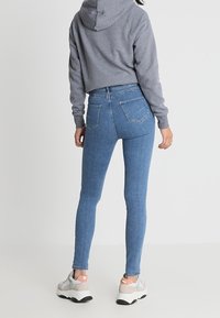 Štíhlé modré džíny s vysokým pasem, elastický denimový materiál, design s pěti kapsami a švy na zadním pásu. V kombinaci se šedou zkrácenou mikinou.