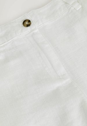 Detailaufnahme von weißen Leinenhosen mit braunem Knopf, Bund und Taschennaht.