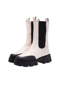 Botas Chelsea en blanco y negro con una suela de goma gruesa, fabricadas en material texturizado, con paneles elásticos y lengüetas para ponerlas y quitarlas fácilmente.