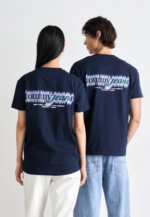 Mørkeblå bomulds T-shirts har "tommy jeans" logo i flerfarvet tekst på ryggen. Båret med lysfarvede jeans og en afslappet pasform.