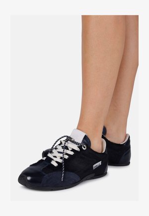 Marineblå sneakers med en kombinasjon av glatte og teksturerte materialer, hvite snører og en distinkt logo som aksent på siden.