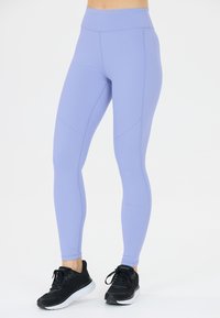 Lila leggings i stretchmaterial, med hög midja, prickiga detaljer längs sidorna och slät yta. Matchas med svarta sneakers.