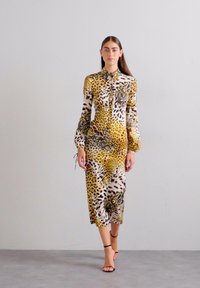 Leopard-print dress in yellow and brown tones, mid-length, long-sleeved with a collar; smooth texture and cinched waist detail.